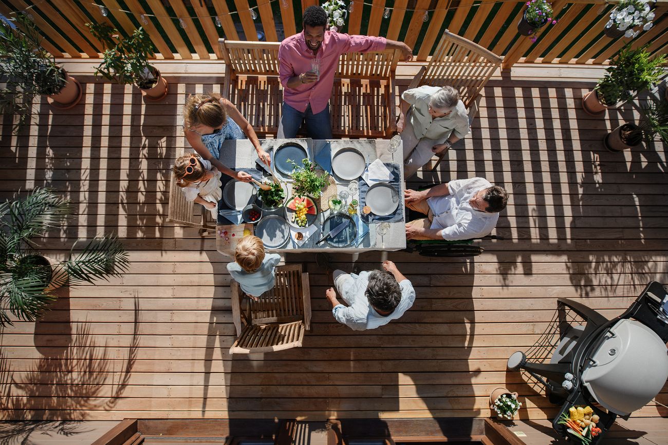 friends enjoying a race day BBQ at home with meats grilling on the BBQ